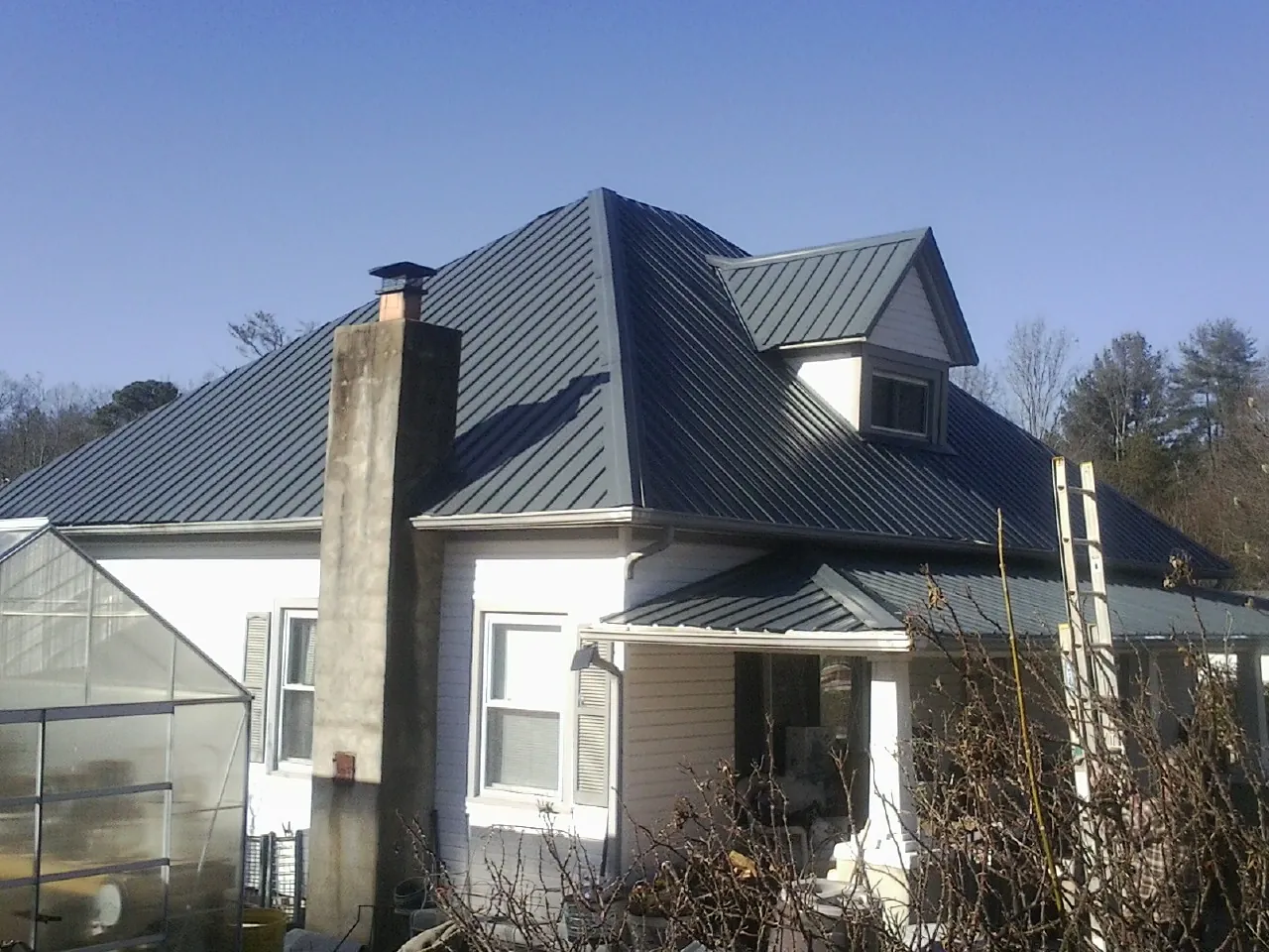 Dark blue standing seam metal roof on a white farmhouse with dormer — Slate & Tile Roof Repair by Roofing Brothers in Spanish Fork