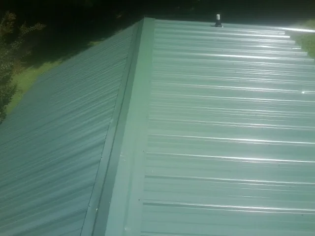 New green metal panels meeting at the ridge of a roof — Flat Roof Repair work by our crew in Spanish Fork