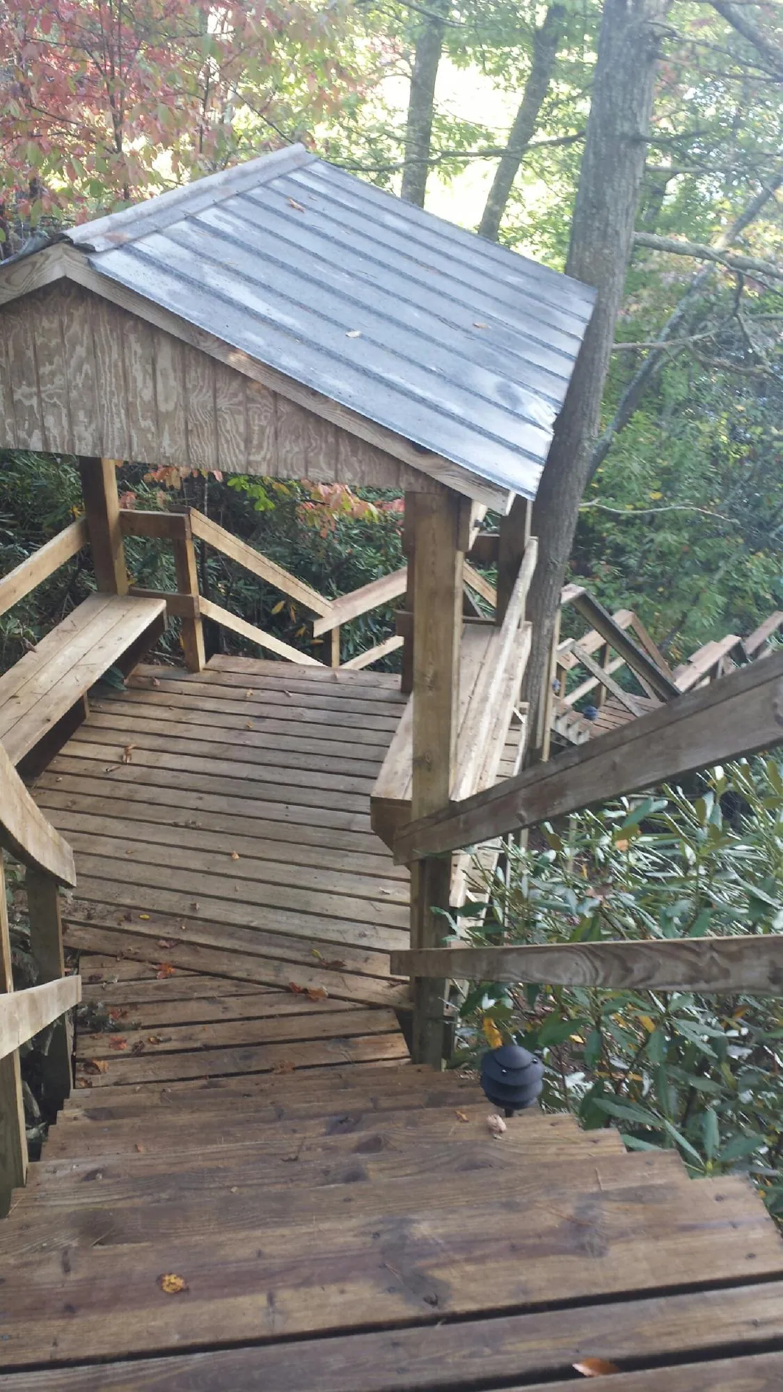 Metal roofed shelter over wooden steps on a wooded walkway — Skylight Repair & Installation work by our crew in Spanish Fork