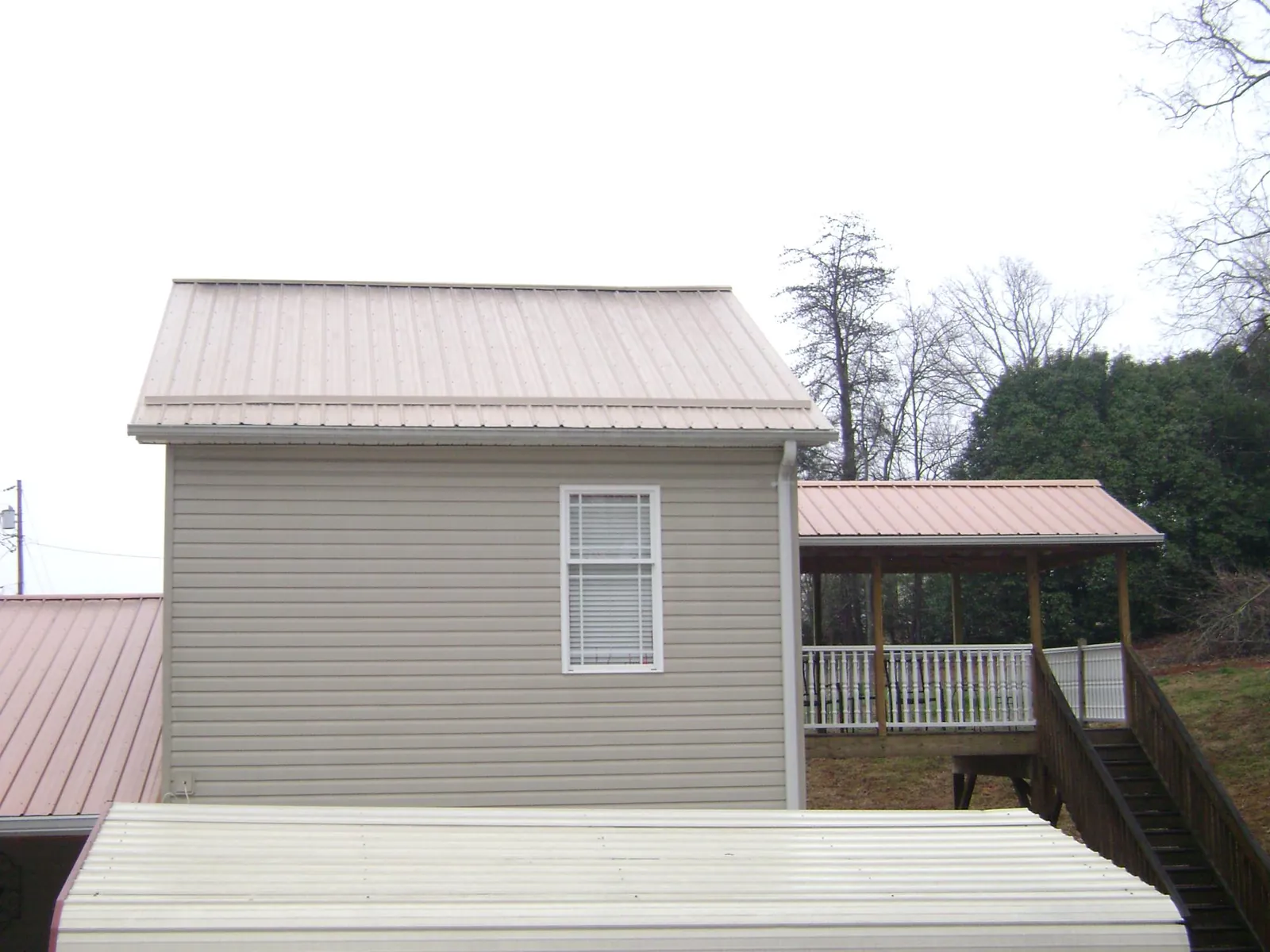 Tan metal roofs on a two story addition and attached porch, from a Roof Replacement job in Spanish Fork