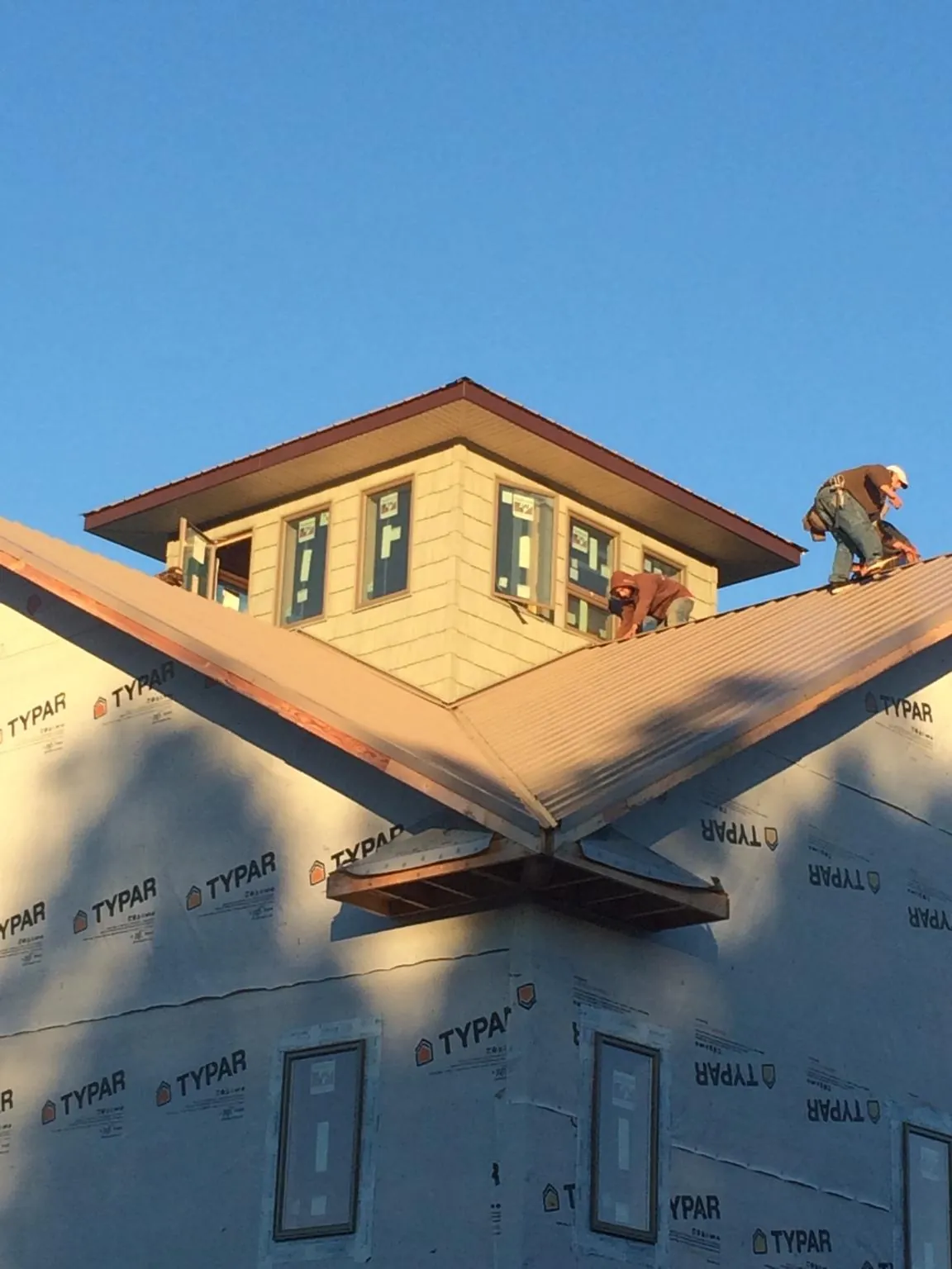 Roofers working around a rooftop cupola on a new metal roof at sunset — Roof Waterproofing in Spanish Fork by Roofing Brothers